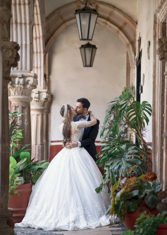 a bride and groom kissing in an archway, inspired by Luis Paret y Alcazar, pexels contest winner, renaissance, mexico, 2 5 6 x 2 5 6 pixels, in balcony of palace, ( ( theatrical ) )