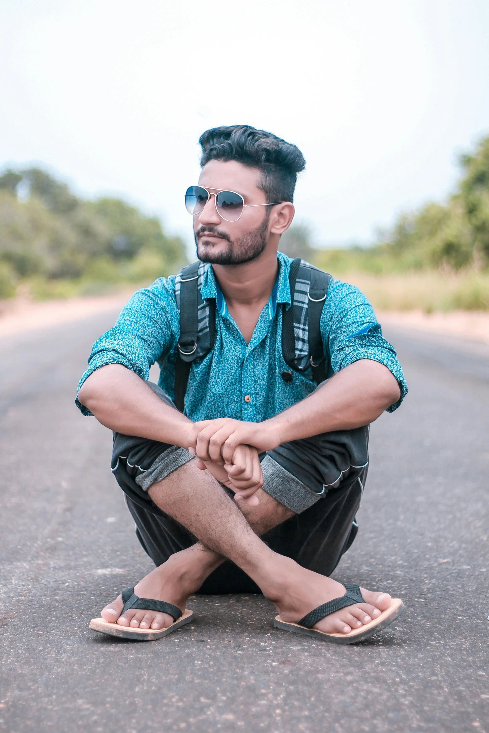 a young man sits on the street in sandals