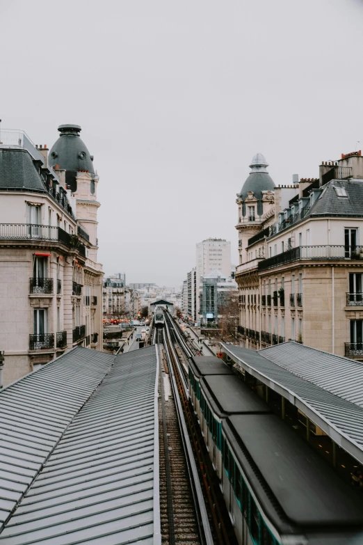 a train traveling down train tracks next to tall buildings, unsplash contest winner, paris school, tiled roofs, no people, square, quiet beauty