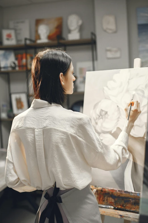 a woman that is standing in front of a painting, wearing white clothes, painting a canvas, professional sketch, over the shoulder