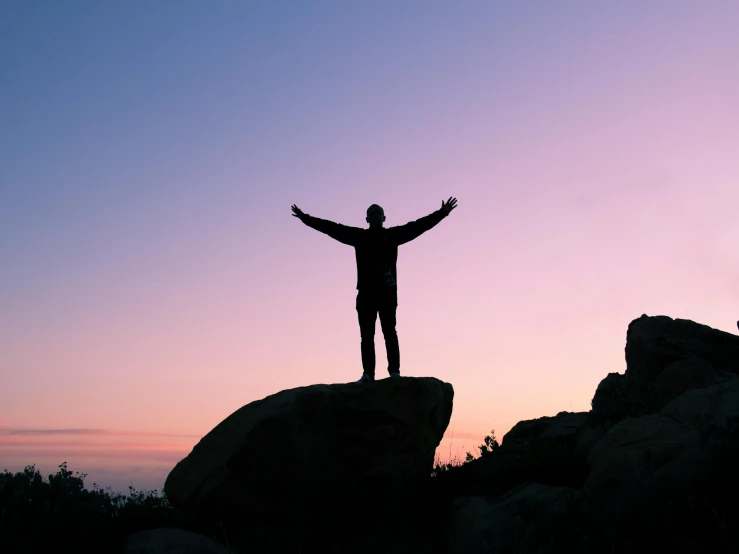 a man standing on top of a large rock, pexels contest winner, standing triumphant and proud, predawn, shrugging arms, standing straight