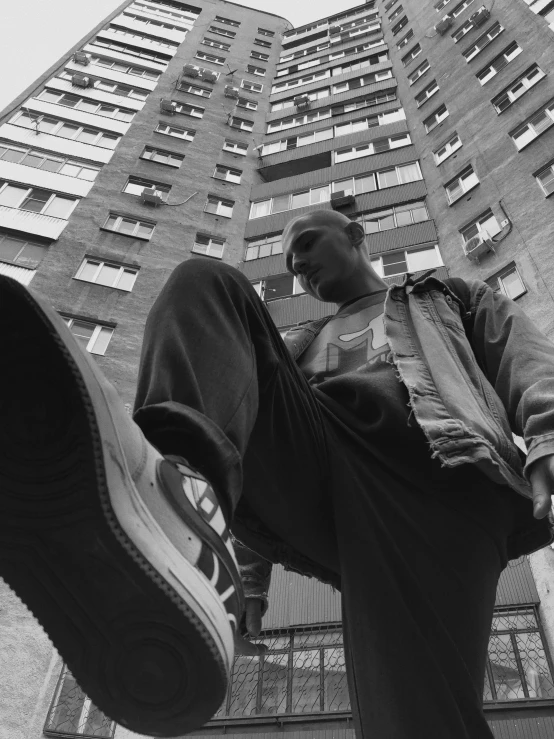 a man standing on top of a skateboard in front of a tall building, by Arthur Sarkissian, portait image, leonid, low detailed, sneaker photo