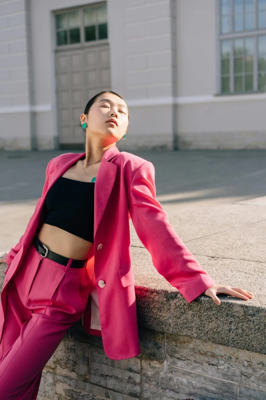 a woman in a pink suit leaning on a wall, an album cover, inspired by Wang E, trending on pexels, berlin fashion, asian sun, wearing a cropped top, ekaterina