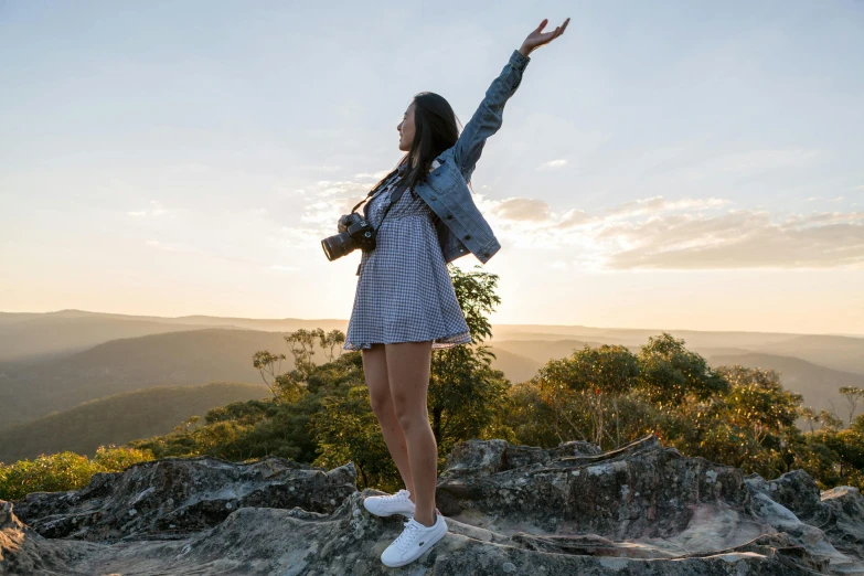 a woman standing on top of a large rock, by Lee Loughridge, pexels contest winner, happening, sydney park, waving arms, profile pic, a young asian woman
