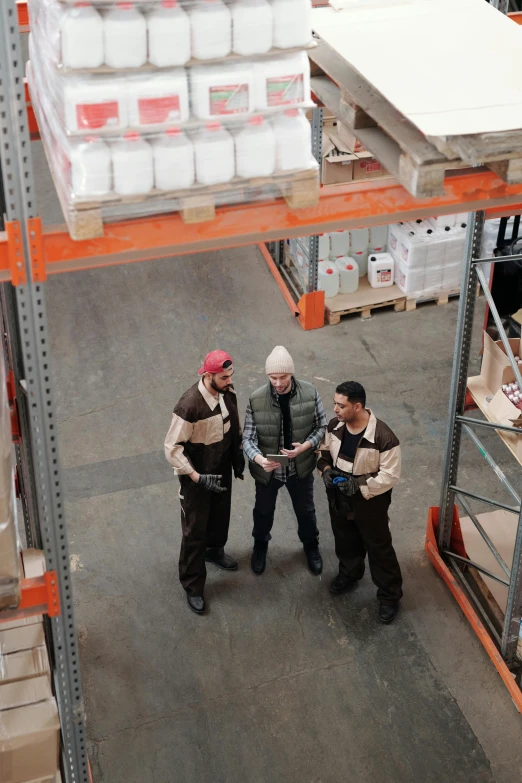 a group of men standing next to each other in a warehouse, pexels contest winner, arbeitsrat für kunst, aerial shot, ilustration, pallet, brown