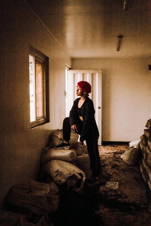 a woman sitting on a couch in a room, inspired by Elsa Bleda, pexels contest winner, red oval turban, standing atop a pile of rubble, looking through a window frame, bright red hair