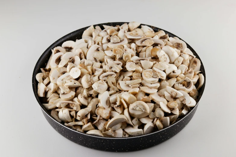 a black bowl filled with mushrooms on top of a white table, high quality product image”, on a gray background, medium blonde, many pieces