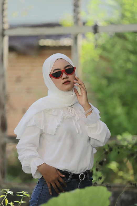 a woman in a white shirt and sunglasses talking on a cell phone, inspired by Naza, trending on pexels, hurufiyya, wearing a long flowy fabric, reds), large)}], frontal picture