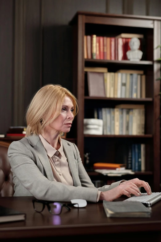 a woman sitting at a desk using a laptop computer, by Edi Rama, shutterstock, still image from tv series, defense attorney, a blond, high resolution photo