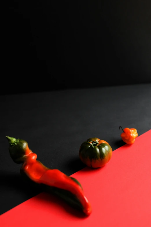 a group of peppers sitting on top of a red and black table, a still life, inspired by Robert Mapplethorpe, unsplash, made of food, mid shot photo, vegetables, contrast lighting