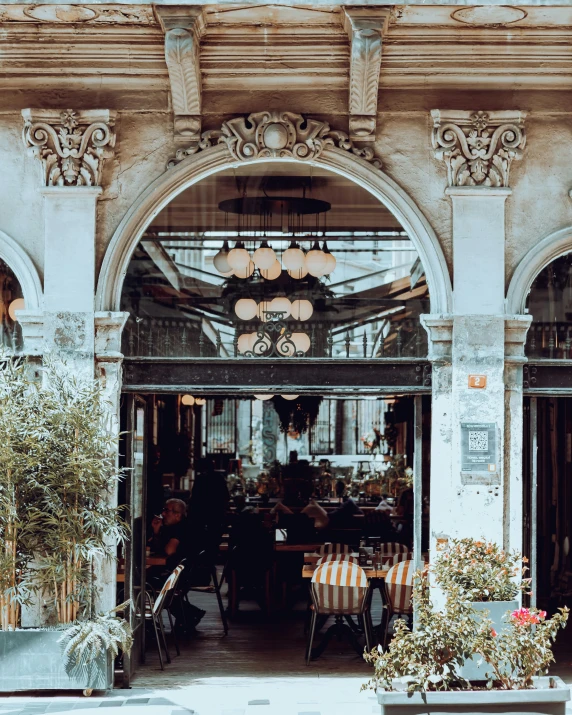 a building with a bunch of potted plants in front of it, a photo, pexels contest winner, art nouveau, cafe interior, steel archways, gif, elegant and ornate