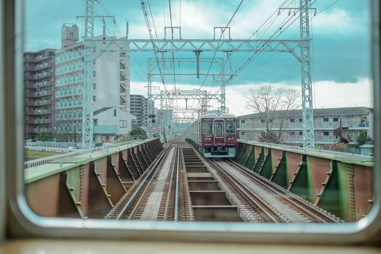 a train traveling down train tracks next to tall buildings, a picture, unsplash, sōsaku hanga, 💋 💄 👠 👗, gopro photo, preserved historical, connecting lines