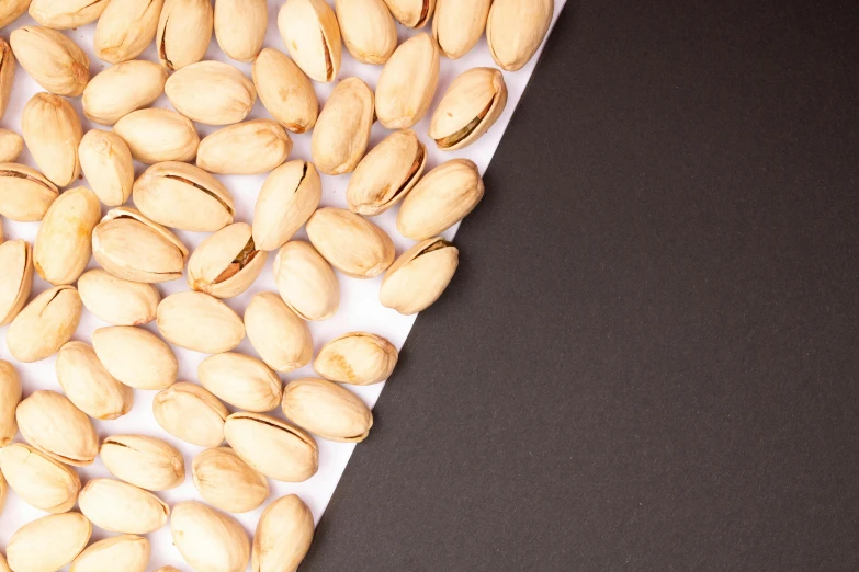 a pile of pistachios sitting on top of a piece of paper, an album cover, by Julia Pishtar, trending on unsplash, 15081959 21121991 01012000 4k, solid background, thumbnail, peanuts