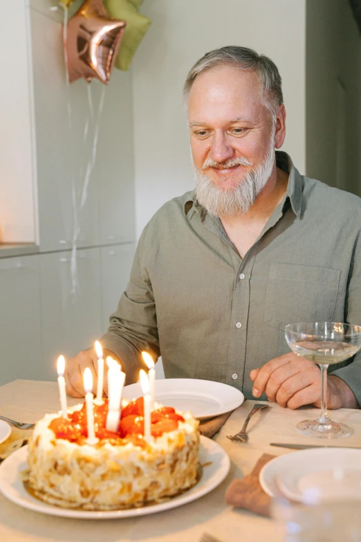 a man sitting at a table with a birthday cake, pexels contest winner, renaissance, gray hair and beard, wholesome, white candles, epicurious