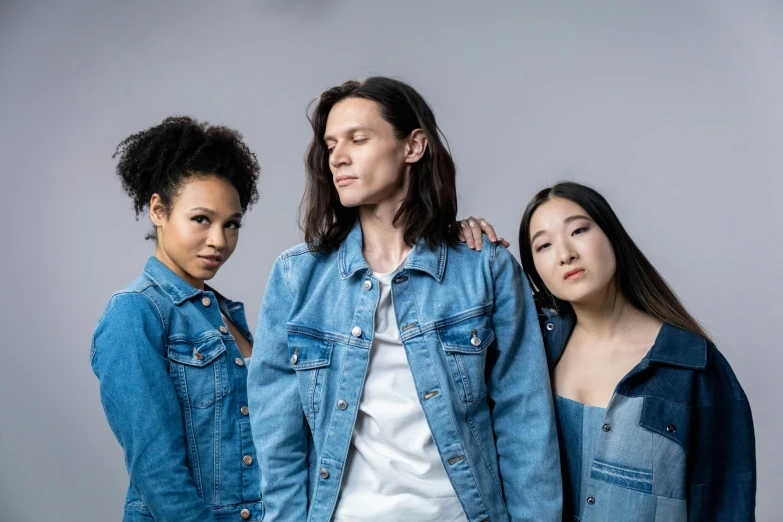 three young women pose together, wearing denims and jackets