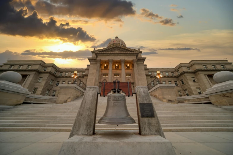 a large bell sitting in front of a building, by Joe Stefanelli, unsplash contest winner, neoclassicism, montana, wide grand staircase, summer evening, capitol riot