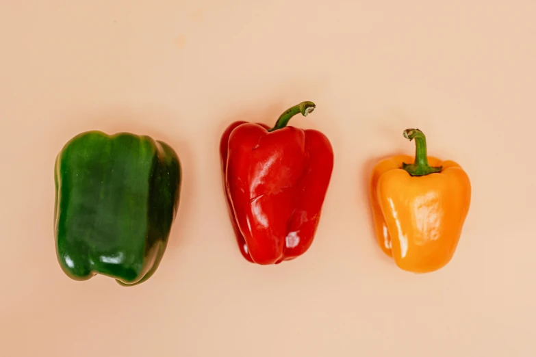 three peppers sitting next to each other on a table, trending on pexels, solid background, peyote colors, warm coloured, 2 years old