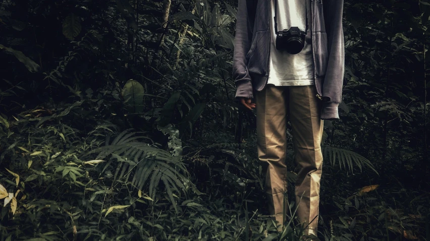 a man standing in the middle of a forest, a picture, unsplash, visual art, wearing cargo pants, camera low, humid alien jungle, casual clothing