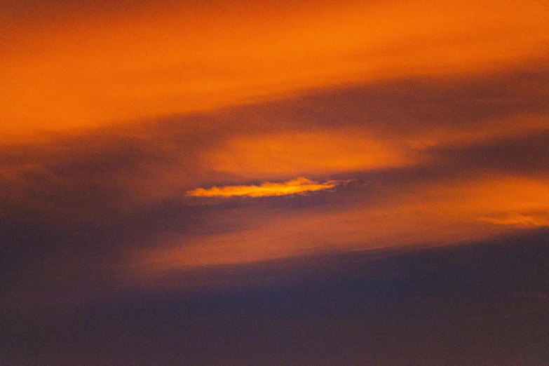 there is a plane that is flying in the sky, by Ian Fairweather, pexels contest winner, romanticism, orange halo, telephoto shot, pareidolia, altostratus clouds