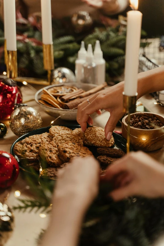 two hands picking up food from a tray in front of some candles