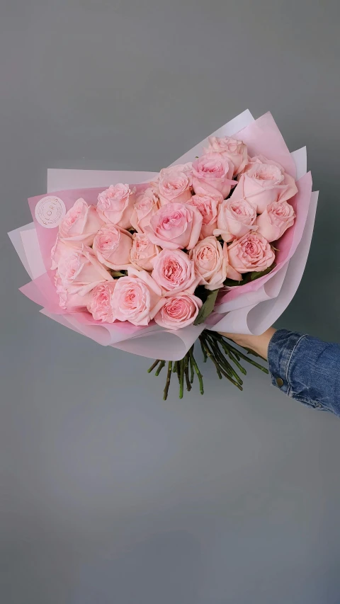 a bouquet of pink roses, wrapped in paper