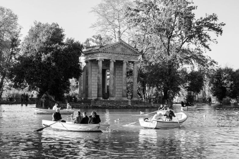 a couple of boats that are in the water, a black and white photo, by Giorgio Cavallon, neoclassicism, time travelers appear in a park, ancient greek temple, everyone having fun, during autumn