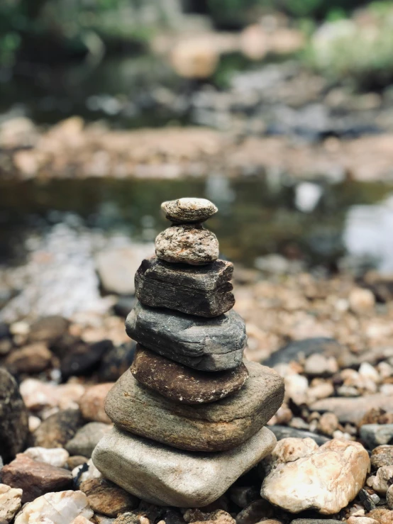 a pile of rocks sitting on top of a rocky beach, inspired by Andy Goldsworthy, unsplash, next to a small river, profile picture, exterior shot, celebration