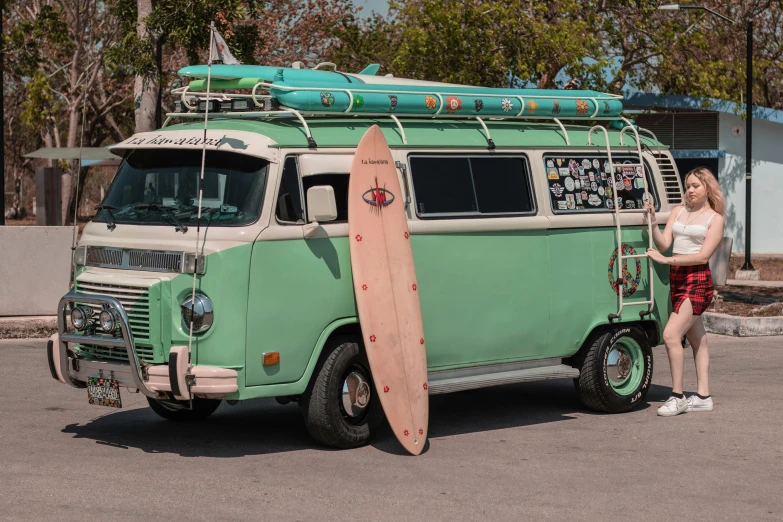 a woman standing next to a green van with a surfboard on top, a colorized photo, pexels contest winner, photorealism, microbus, tubes, hollister ranch, avatar image