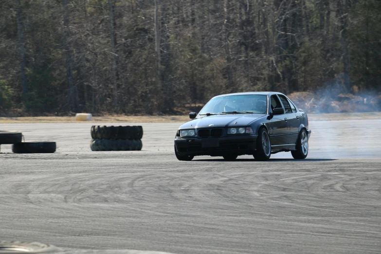 a blue car driving on a road in the woods