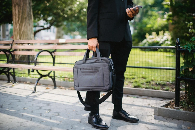 a man in a suit and tie holding a briefcase, pexels contest winner, renaissance, in a city park, in gunmetal grey, bags on ground, multi - layer