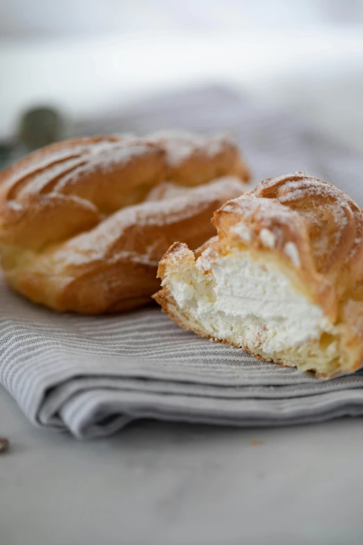 a couple of doughnuts sitting on top of a napkin, inspired by Károly Patkó, light cream and white colors, frozen, breads, molten