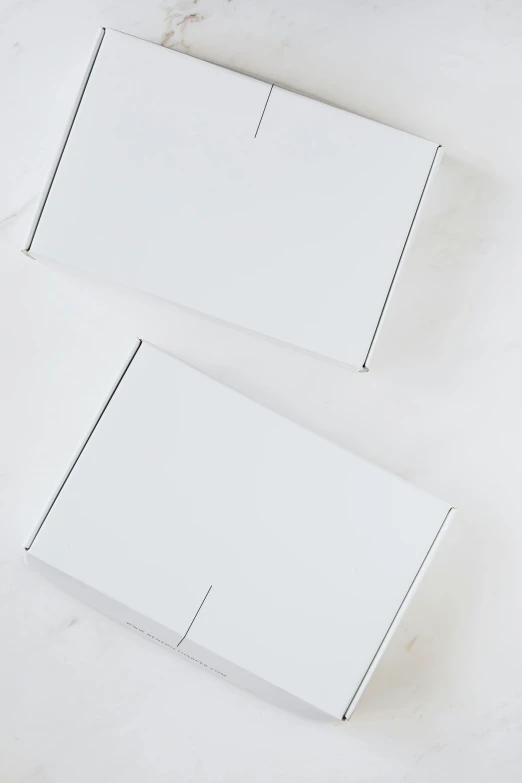 a couple of boxes sitting on top of a table, matte white background, on white paper, back facing the camera, all white