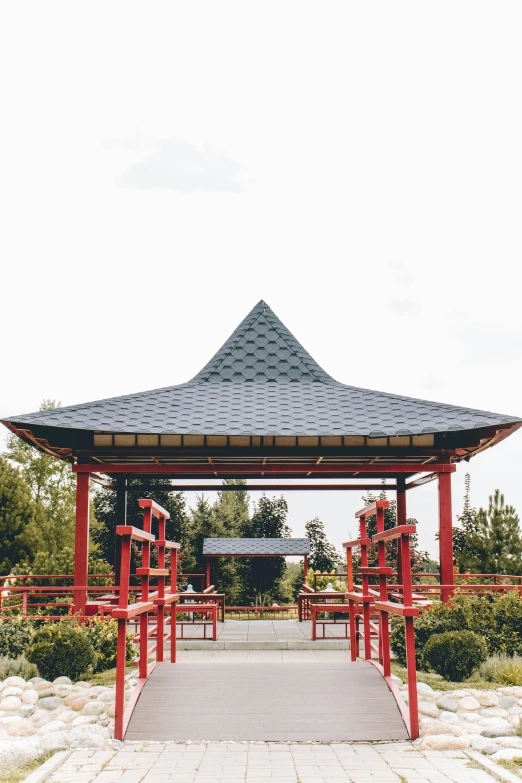 an outdoor gazebo with red posts in front of trees