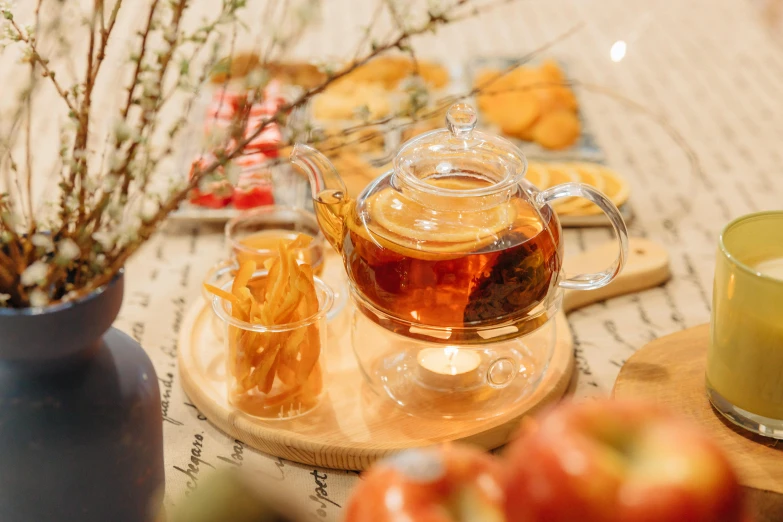 a tea pot sitting on top of a wooden table, a still life, by Julia Pishtar, trending on pexels, renaissance, snacks, glass tableware, sichuan, festive