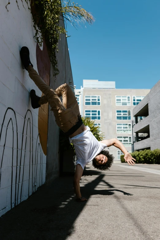 a man doing a handstand on the side of a building, unsplash, graffiti, bay area, classic dancer striking a pose, summer weather, ignant