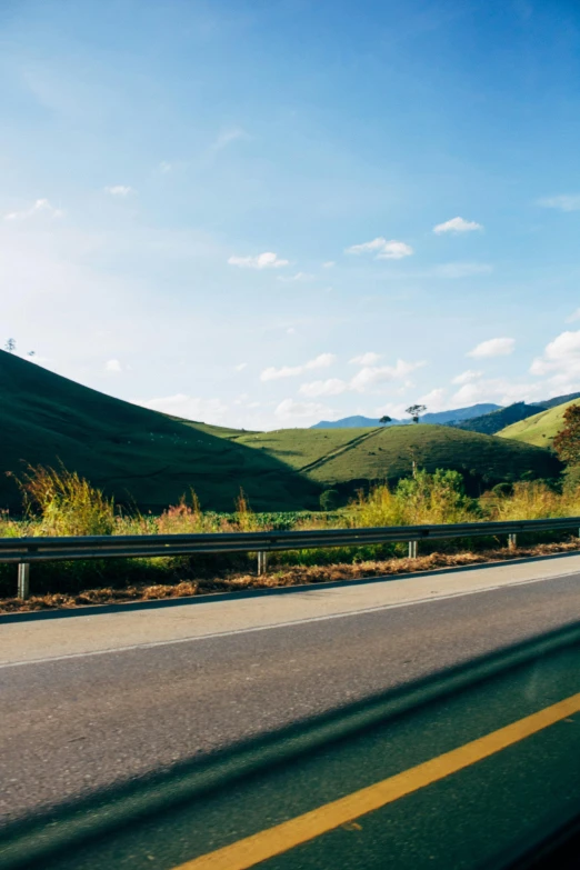 a man riding a skateboard down the side of a road, rolling green hills, billboard image, ultrawide image, city of armenia quindio