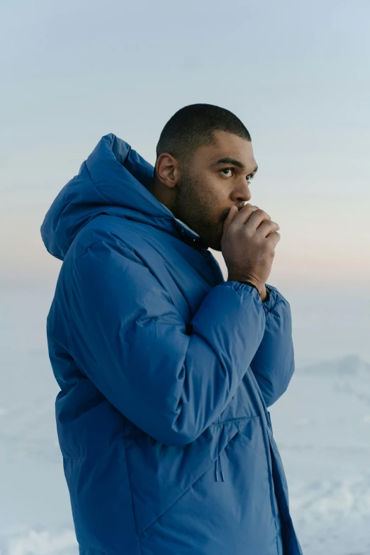 a man in a jacket standing in snow looking off into the distance