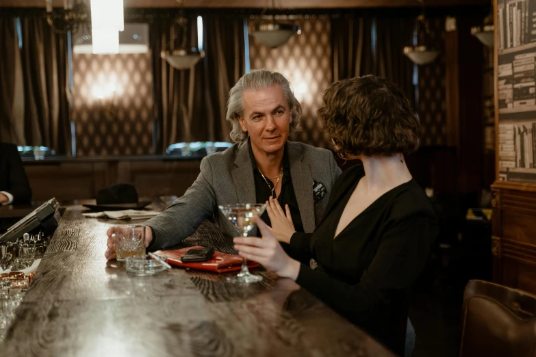 a group of people sitting at a bar, a portrait, by Emma Andijewska, pexels, happening, dark grey haired man, medium shot of two characters, on a wooden table, calmly conversing 8k