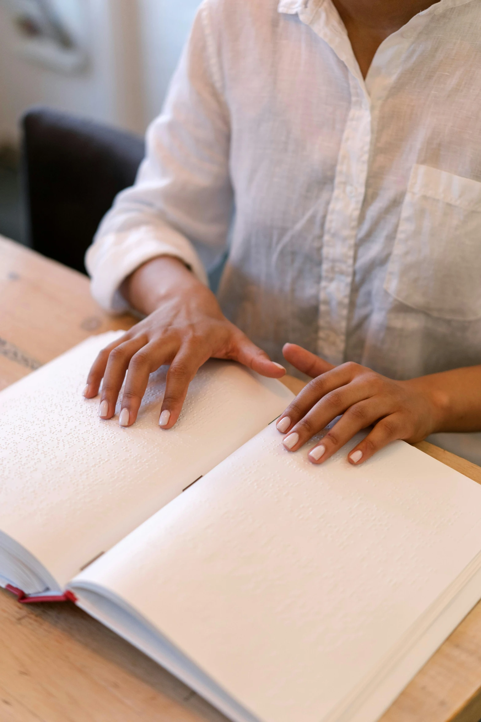 a woman sitting at a table with an open book, process art, sleek hands, curated collections, white, manual