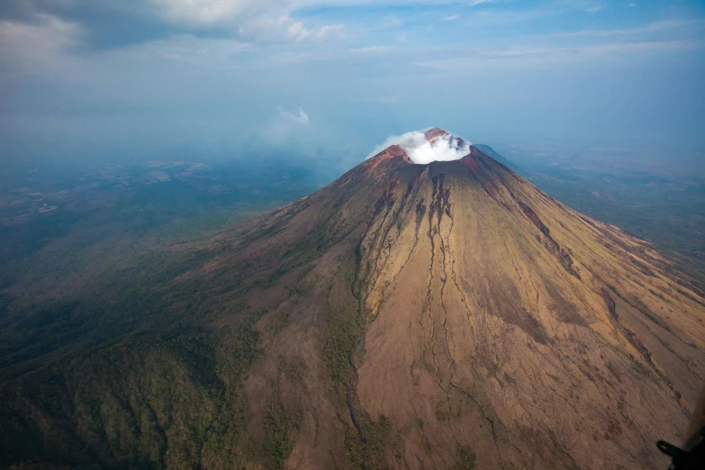 a large mountain covered in clouds near some trees