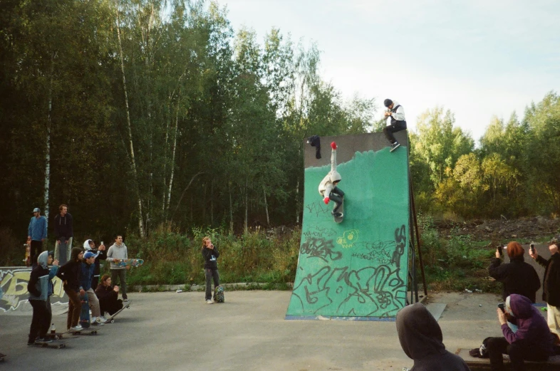 a man riding a skateboard up the side of a ramp, by Anato Finnstark, lots of people, softair center landscape, abdulov, a green