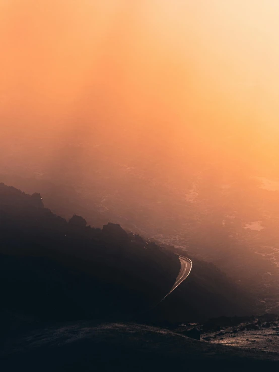 a person standing on top of a mountain at sunset, a matte painting, unsplash contest winner, romanticism, light orange mist, gulf of naples, road between hills, today\'s featured photograph 4k