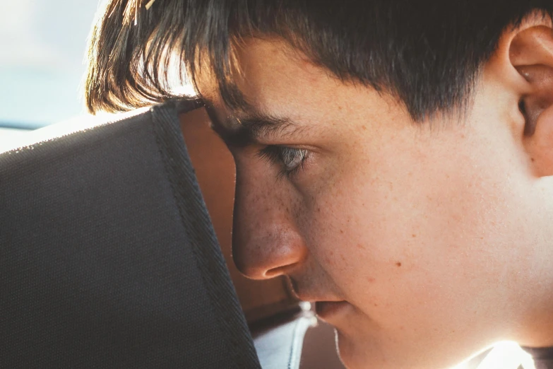 a close up of a person looking at a laptop, by Carey Morris, pexels contest winner, hyperrealism, 14 yo berber boy, head bowed slightly, pouty face, afternoon sunshine