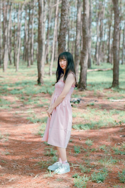 a woman standing in the middle of a forest, a picture, by Sengai, unsplash, visual art, wearing a pink dress, low quality photo, casual pose, medium format. soft light