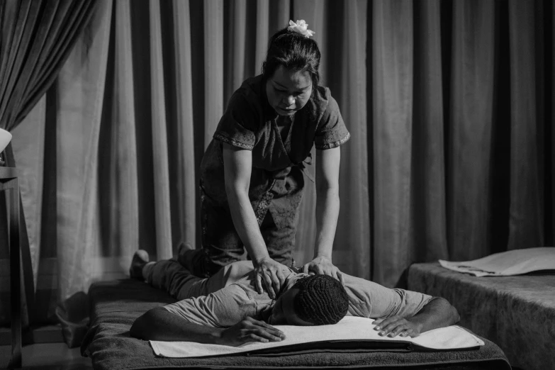 a black and white photo of a man getting a massage, by Emma Andijewska, renaissance, cambodia, still from a live action movie, low iso, sports photo