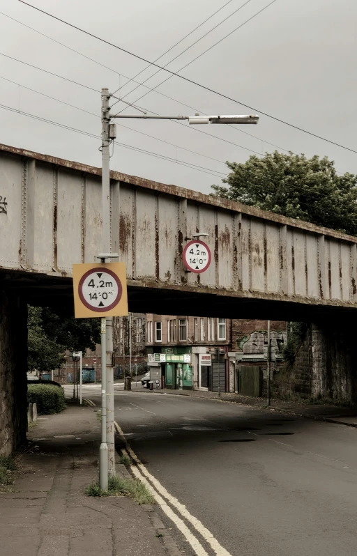 a couple of signs that are on the side of a road, by Chippy, street art, suspended bridge!, railway tracks going through it, ((rust)), traffic signs