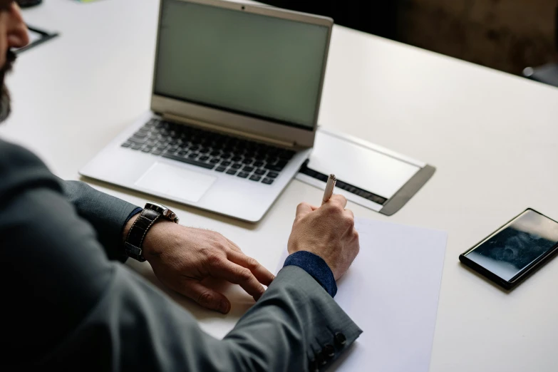 a man sitting at a table with a laptop and cell phone, a computer rendering, pexels contest winner, hurufiyya, writing on a clipboard, court session images, corporate business, slightly minimal