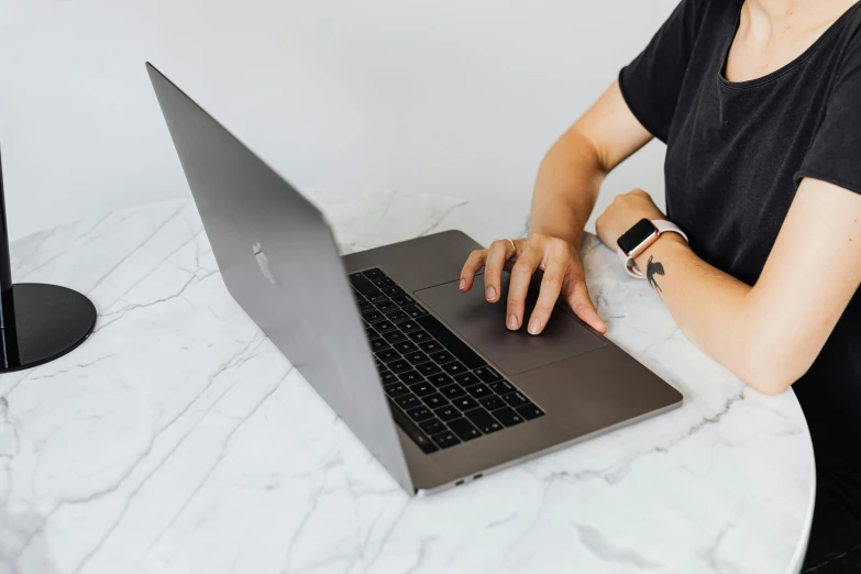 a woman sitting at a table with a laptop, by Carey Morris, pexels, smooth marble surfaces, apple design, background image, black jewellery