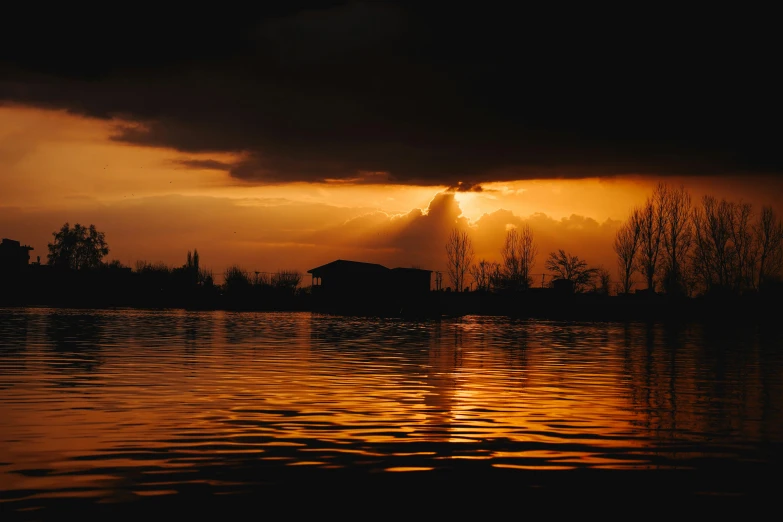 the sun rising behind a cloud is reflecting on water