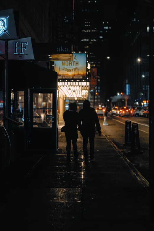 two people walking down a city street at night, poster art, by Niko Henrichon, pexels contest winner, happening, broadway, marquee, lovers, new york back street